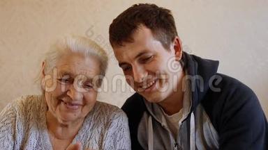 快乐年轻人的慢动作肖像教他年迈的祖母使用智能手机。